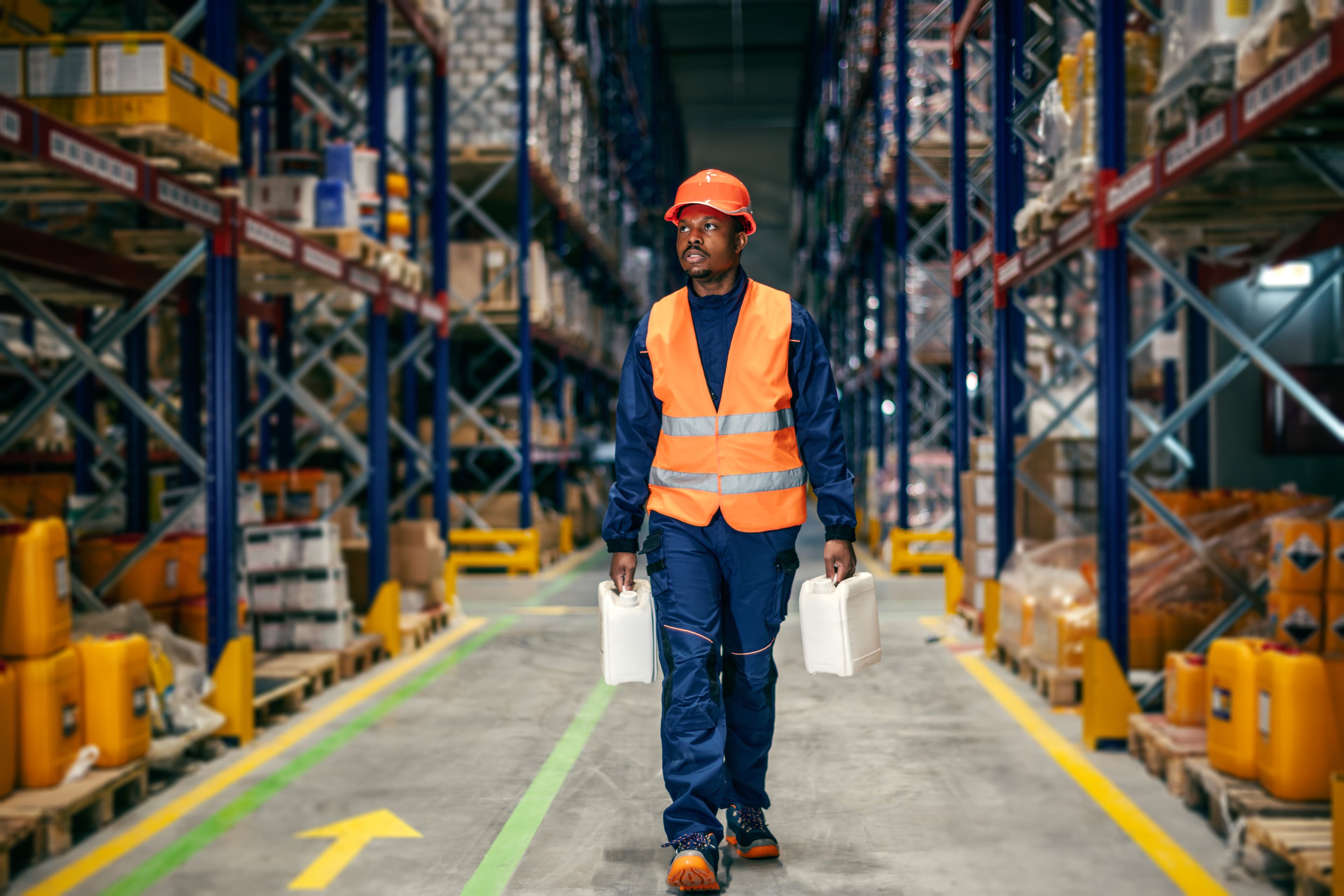 Operator carrying jerry cans in the warehouse